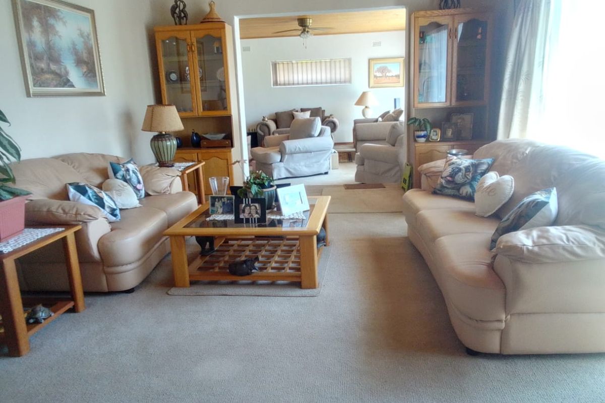 Spacious living room featuring neutral carpeting and built-in display cabinetry, with an open-plan flow leading into an adjacent lounge area.