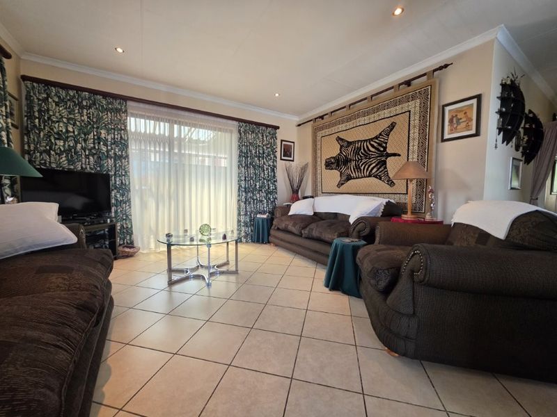 Spacious living room featuring tiled flooring, recessed downlighting, and a large sliding glass door providing access to the outdoor area.