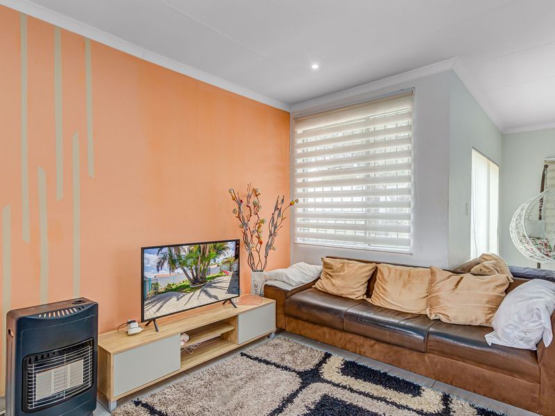 A bright living room featuring tiled flooring, recessed downlighting, and a built-in gas heater, offering a comfortable and functional space.