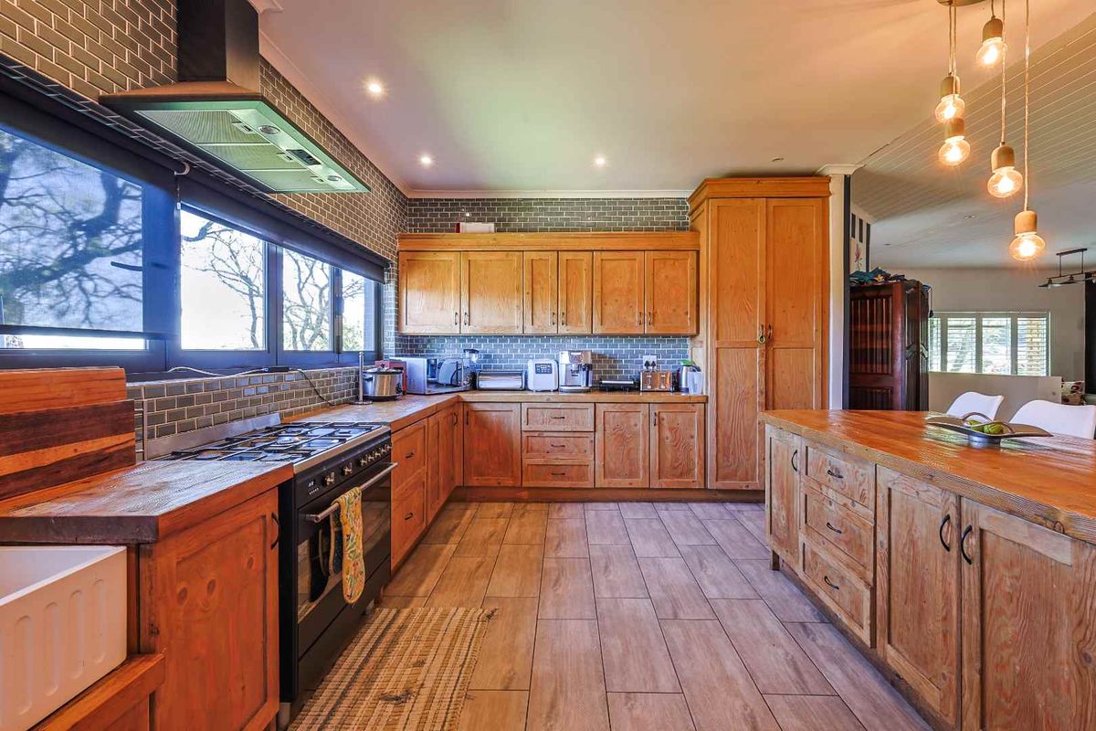 Spacious kitchen featuring custom wooden cabinetry, a large central island with a wooden countertop, a gas stove, and stylish subway tile backsplash.