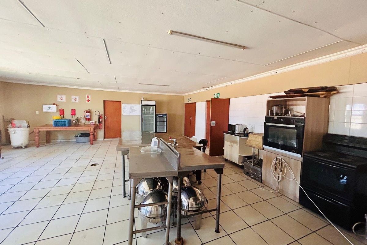 Commercial kitchen space featuring stainless steel prep tables, built-in oven, tiled flooring, and multiple access doors.