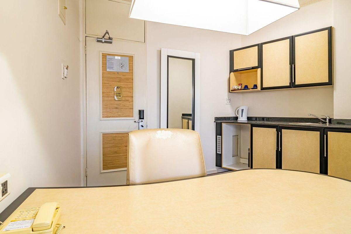 A compact kitchenette featuring built-in cabinetry, laminate countertops, and a stainless steel sink, suitable for a studio or apartment setting.