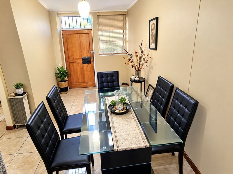 A functional dining area featuring tiled flooring and direct access to the main entrance door with security features.