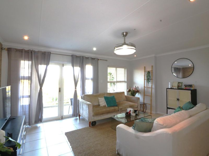A bright and spacious living room featuring tiled flooring, recessed lighting, a ceiling fan, and double glass doors providing access to the outdoor area.