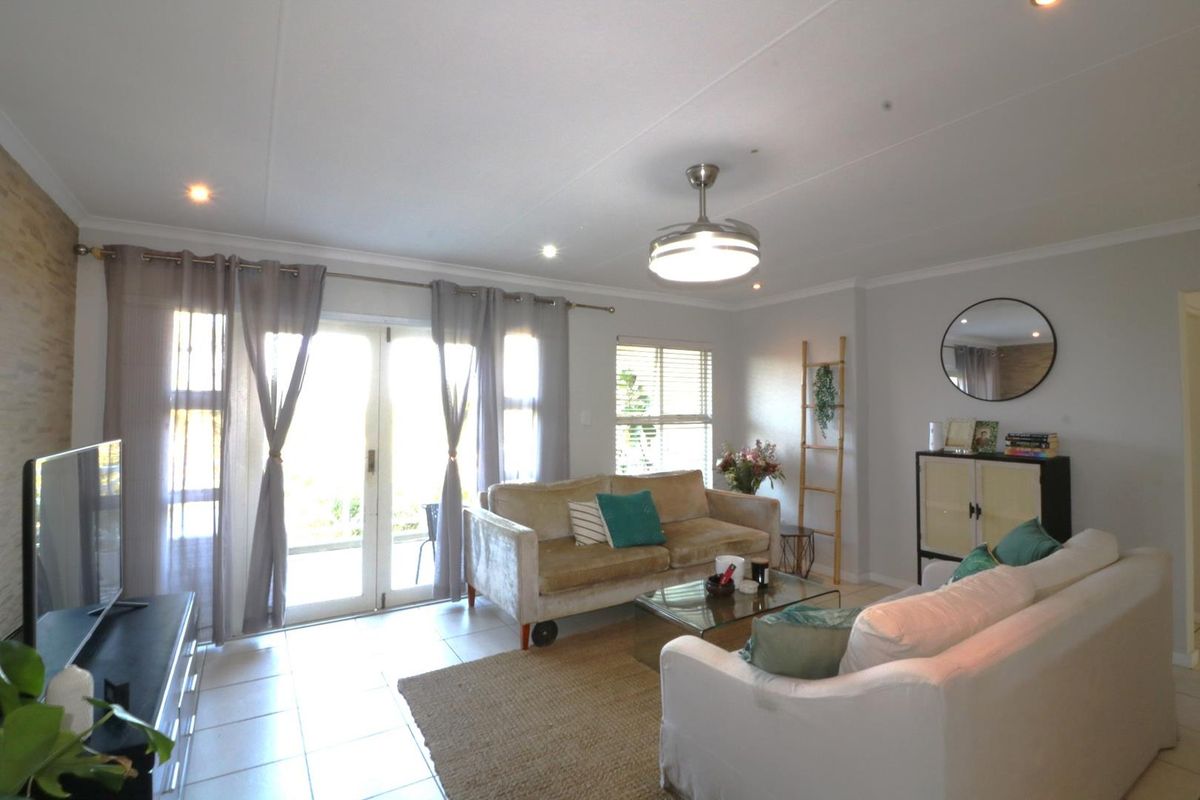 A bright and spacious living room featuring tiled flooring, recessed lighting, a ceiling fan, and double glass doors providing access to the outdoor area.