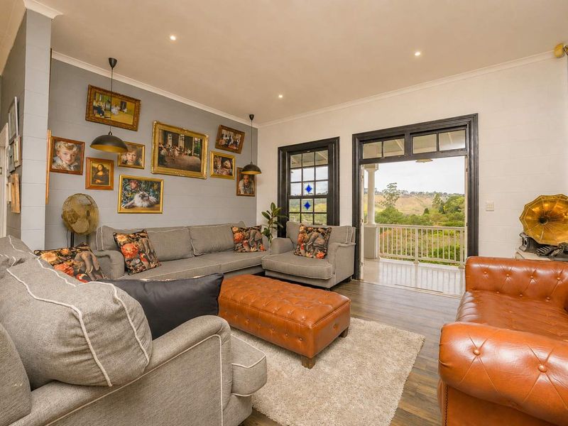 Spacious living room featuring timber flooring, recessed lighting, and direct access to a covered balcony with scenic views.