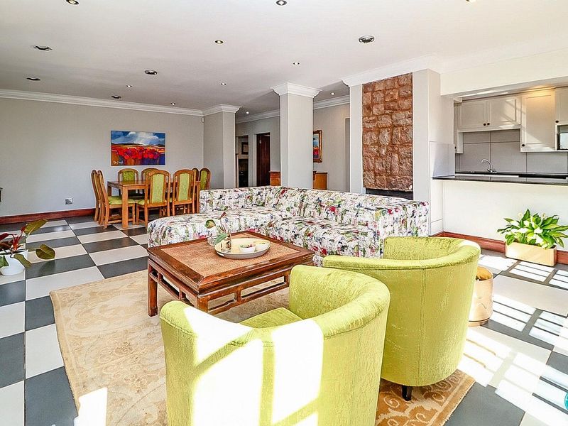 Spacious open-plan living and dining area featuring a stone-clad fireplace, recessed lighting, and a functional kitchen with granite countertops.