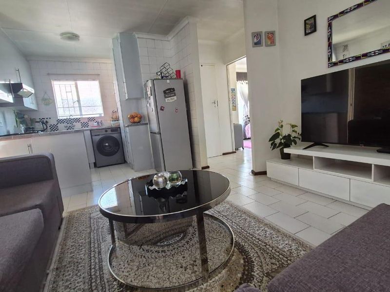 Open-plan living area featuring a functional kitchen with tiled flooring and built-in cabinetry, seamlessly flowing into the lounge space.