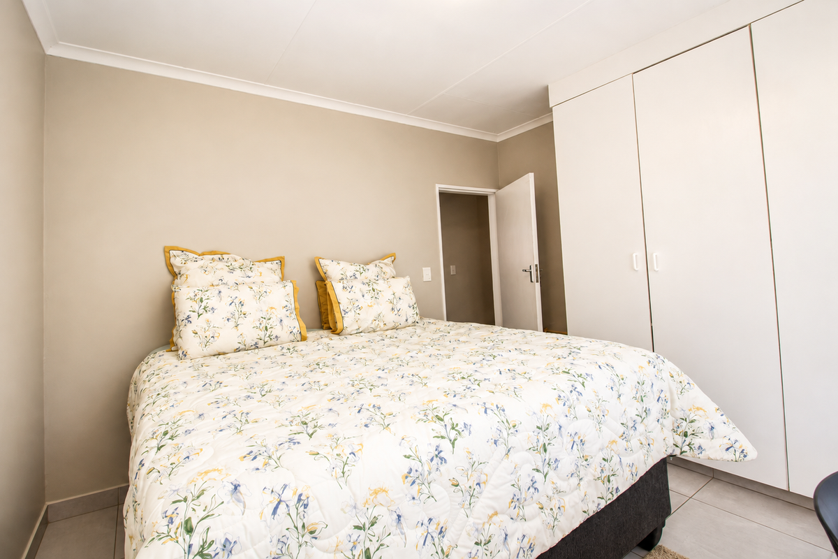 A well-maintained bedroom featuring neutral wall tones, tiled flooring, and ample built-in cupboard storage.