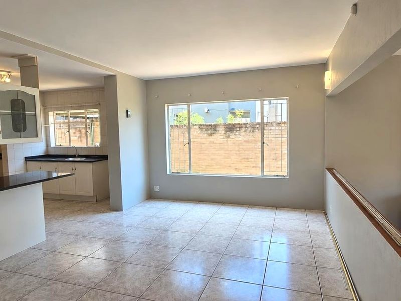 Spacious open-plan living and kitchen area featuring tiled floors, a breakfast bar, and a built-in fireplace, offering a versatile layout for modern living.