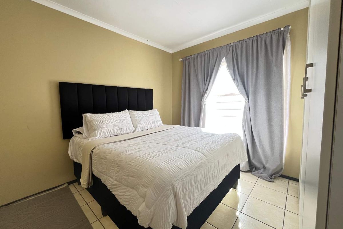 A functional bedroom featuring tiled flooring, neutral wall tones, and a built-in wardrobe, offering a clean and practical living space.