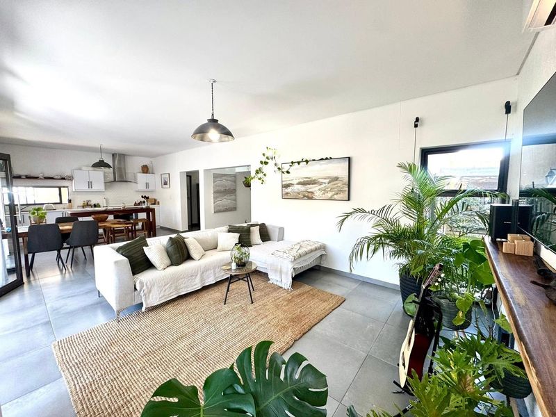 Spacious open-plan living and kitchen area featuring modern tiled flooring, neutral walls, and integrated kitchen cabinetry with contemporary lighting fixtures.