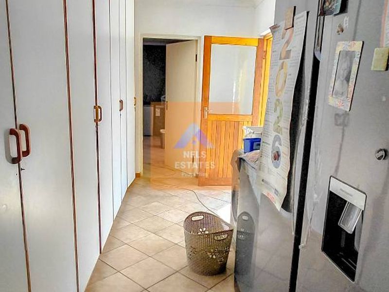 A functional laundry area featuring extensive built-in storage cupboards and tiled flooring, providing practical utility space for the home.