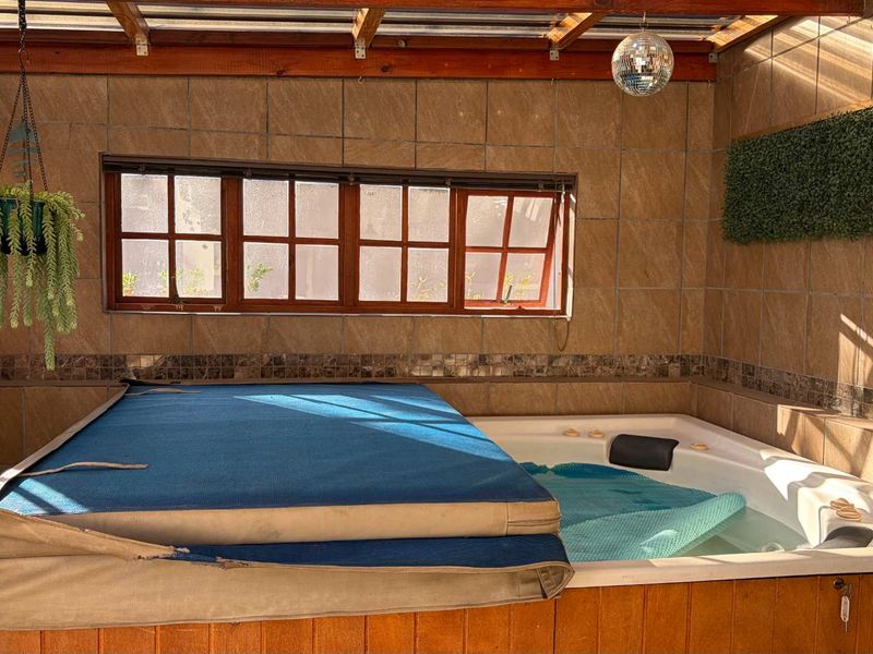 Enclosed patio area featuring a built-in hot tub with a timber-framed roof structure and tiled wall finishes.