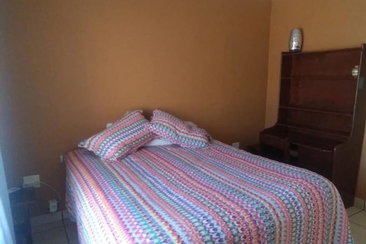 A bedroom featuring tiled flooring and neutral wall finishes, providing a functional space for rest.