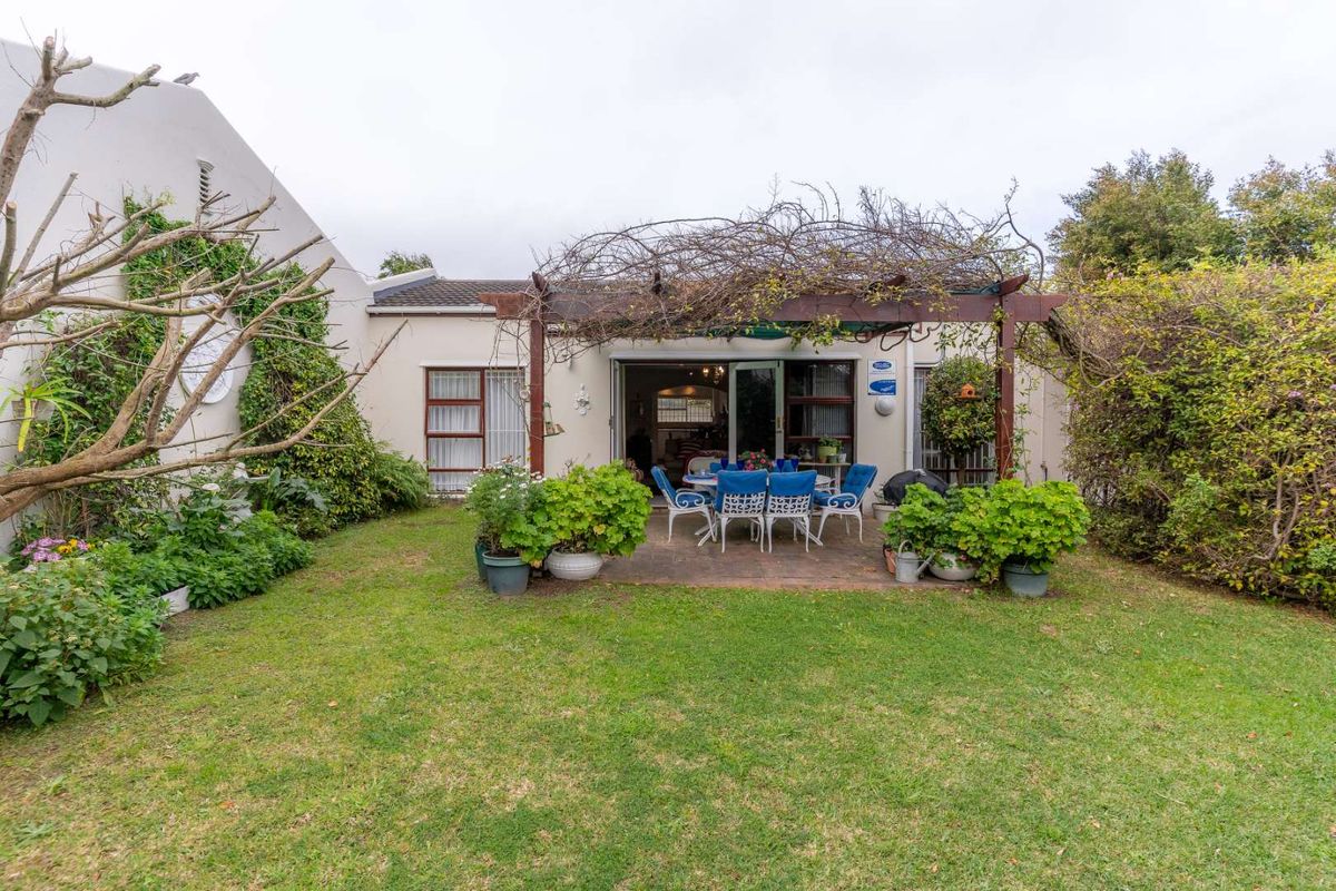 Rear view of the property featuring a paved patio area with a timber pergola, sliding door access, and a private garden.
