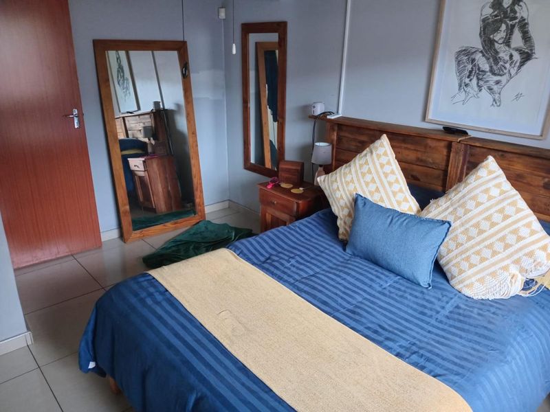 A bedroom featuring tiled flooring and a wooden door, with a visible paint patch on the wall requiring minor cosmetic attention.
