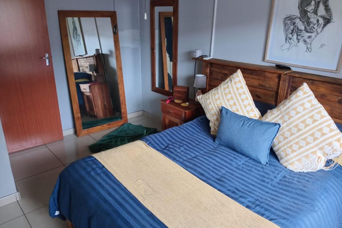 A bedroom featuring tiled flooring and a wooden door, with a visible paint patch on the wall requiring minor cosmetic attention.