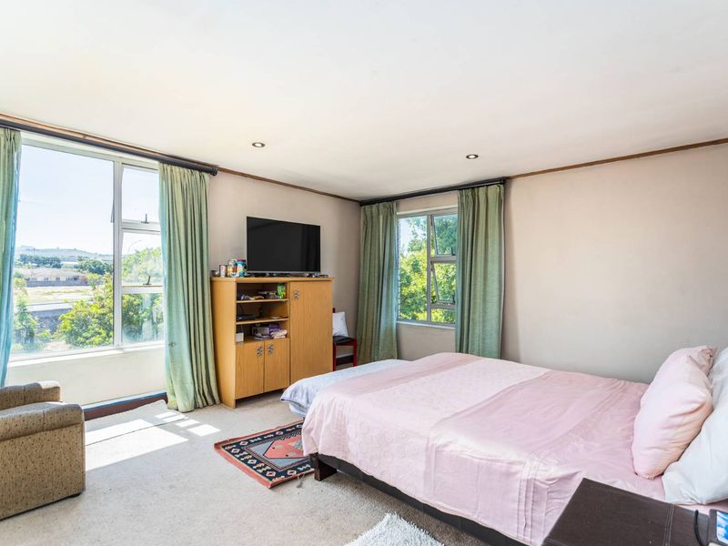 A spacious bedroom featuring large windows that provide ample natural light and scenic views, complemented by recessed downlighting.