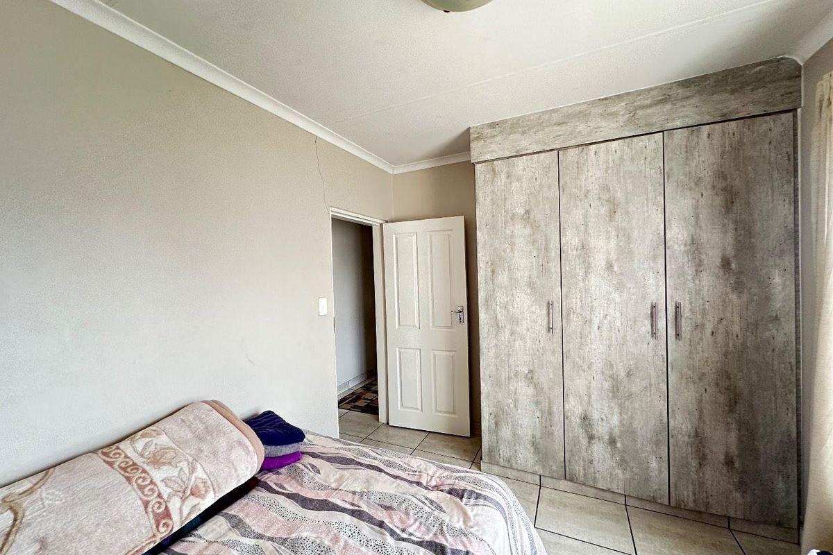 A bedroom featuring built-in cupboards with a wood-look finish and tiled flooring.