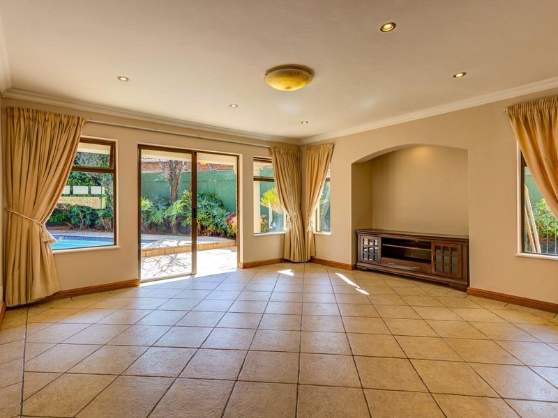Spacious living room featuring tiled flooring, recessed lighting, and a sliding glass door providing direct access to the outdoor pool area.