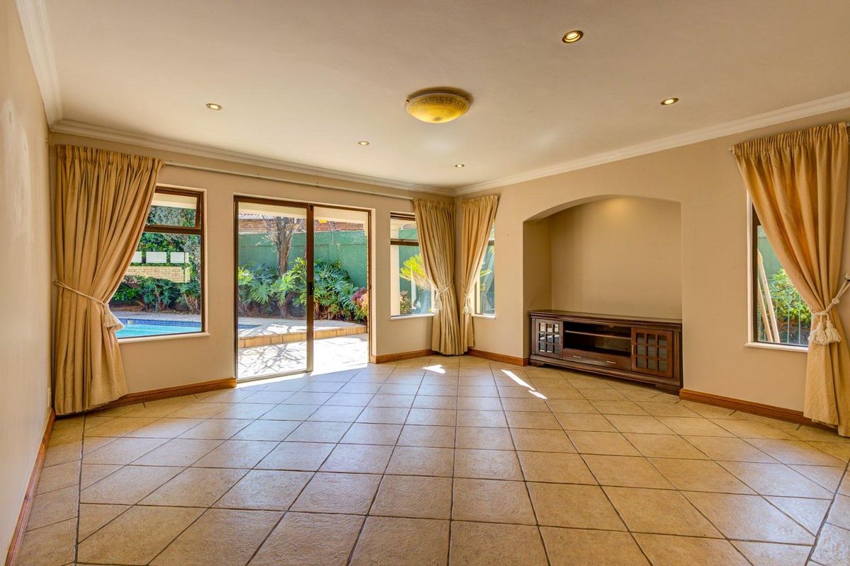 Spacious living room featuring tiled flooring, recessed lighting, and a sliding glass door providing direct access to the outdoor pool area.