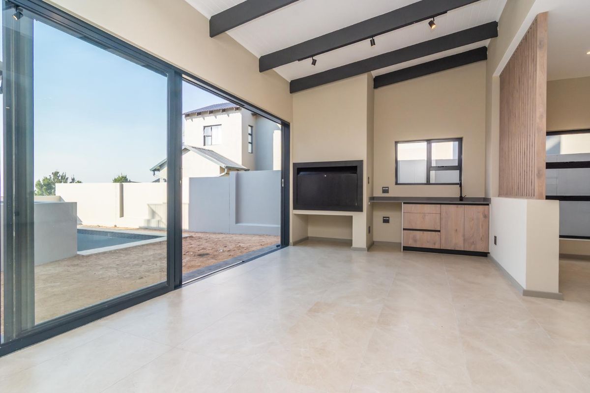 Spacious living area featuring exposed ceiling beams, a built-in fireplace, and large sliding glass doors opening to the outdoor pool area.