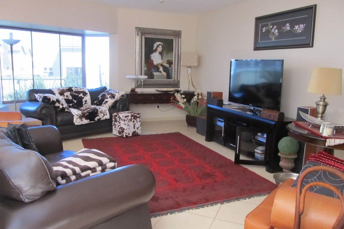 Spacious living room featuring large windows, tiled flooring, and recessed ceiling lighting, providing a comfortable and well-lit area for relaxation.