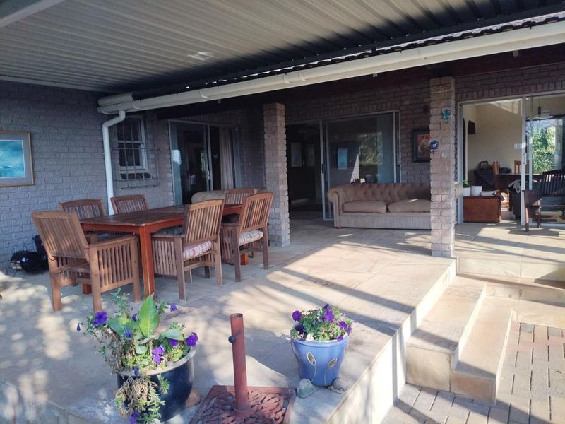 A spacious covered patio featuring brick pillars, paved flooring, and direct access to the interior living areas through sliding glass doors.