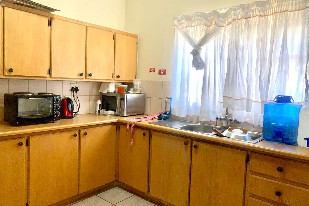 A dated kitchen featuring wooden cabinetry, laminate countertops, and a double-basin stainless steel sink with tiled splashbacks.