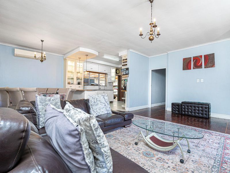 Spacious open-plan living and dining area featuring hardwood floors, light blue walls, and a well-appointed kitchen with built-in cabinetry.