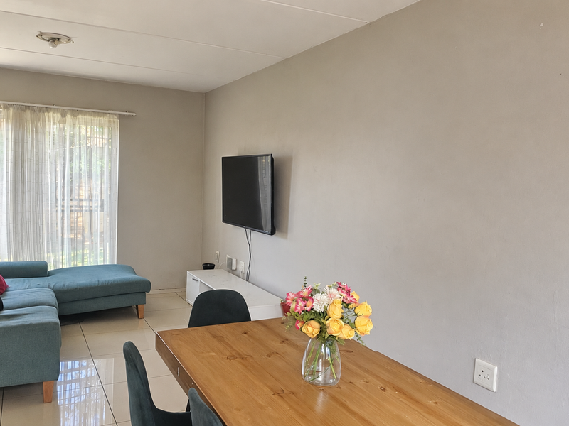 An open-plan living and dining area featuring neutral walls, tiled flooring, and a sliding glass door providing access to the outdoor space.