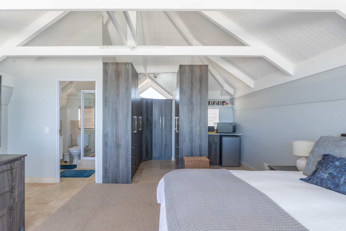 Spacious bedroom featuring vaulted ceilings, built-in cabinetry, and an en-suite bathroom with modern finishes.