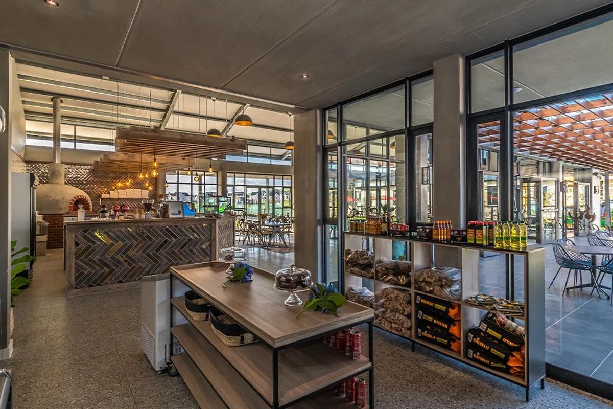 Modern clubhouse interior featuring a built-in pizza oven, stylish herringbone tile counter, and expansive glass doors opening to an outdoor patio area.