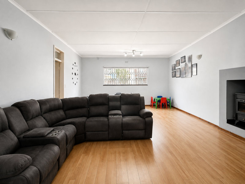 Spacious living room featuring light laminate flooring, a built-in fireplace, and neutral walls, offering a versatile layout for comfortable family living.