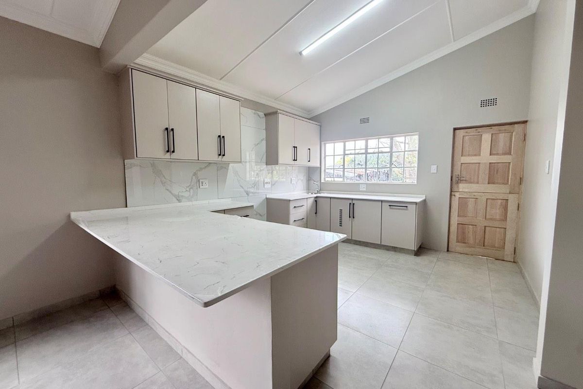 Modern kitchen featuring marble-look quartz countertops, ample built-in cabinetry, tiled flooring, and a clean, neutral aesthetic in an open-plan layout.