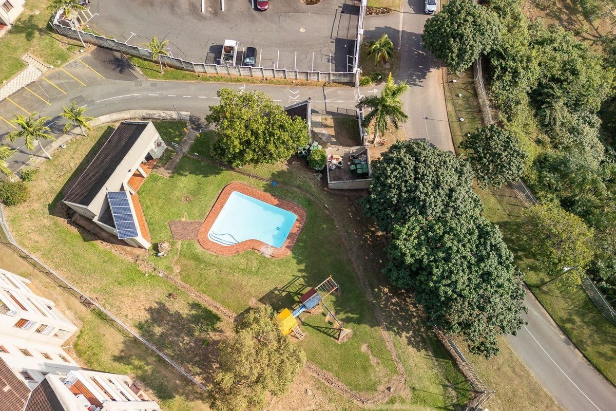 Aerial view of the apartment complex grounds featuring a swimming pool, solar panels, and landscaped communal garden areas.