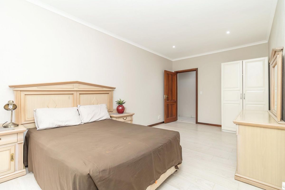 A spacious bedroom featuring light-toned wood-look flooring, recessed ceiling lighting, and built-in cabinetry.
