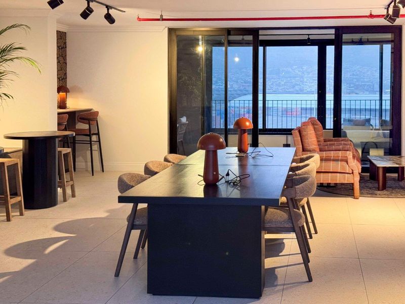 Spacious open-plan living and dining area featuring modern tiled flooring, track lighting, and large sliding glass doors leading to a balcony with city views.