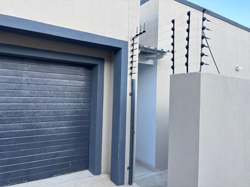 Front exterior view of the property featuring a secure roll-up garage door and perimeter electric fencing.