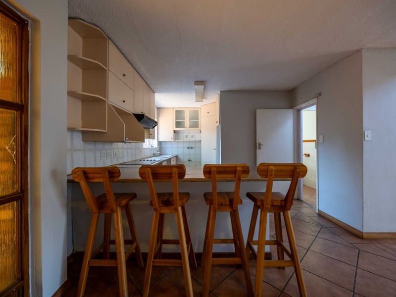 A functional kitchen featuring built-in cabinetry, a breakfast counter, and tiled flooring, offering a practical layout for daily use.