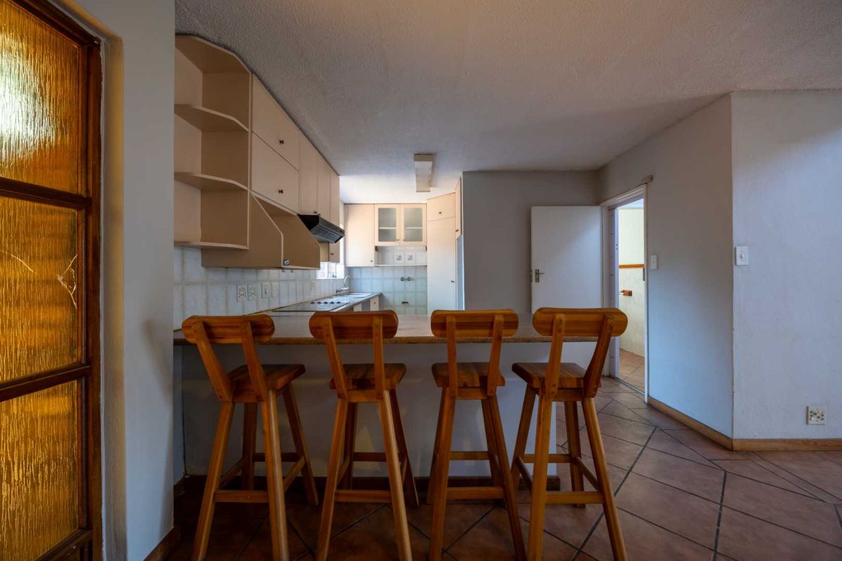 A functional kitchen featuring built-in cabinetry, a breakfast counter, and tiled flooring, offering a practical layout for daily use.