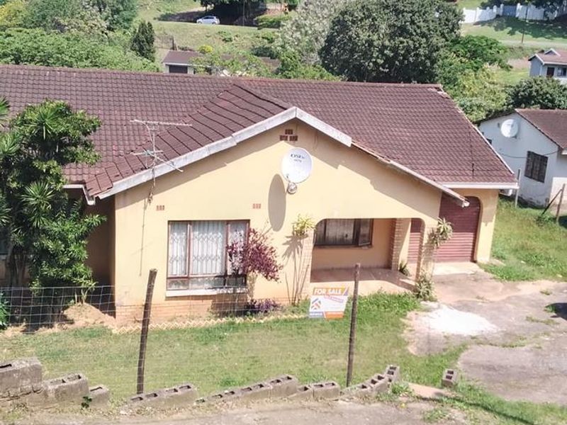Front view of a single-story residential house featuring a tiled roof, covered entrance, and attached garage, situated on a sloped lot.