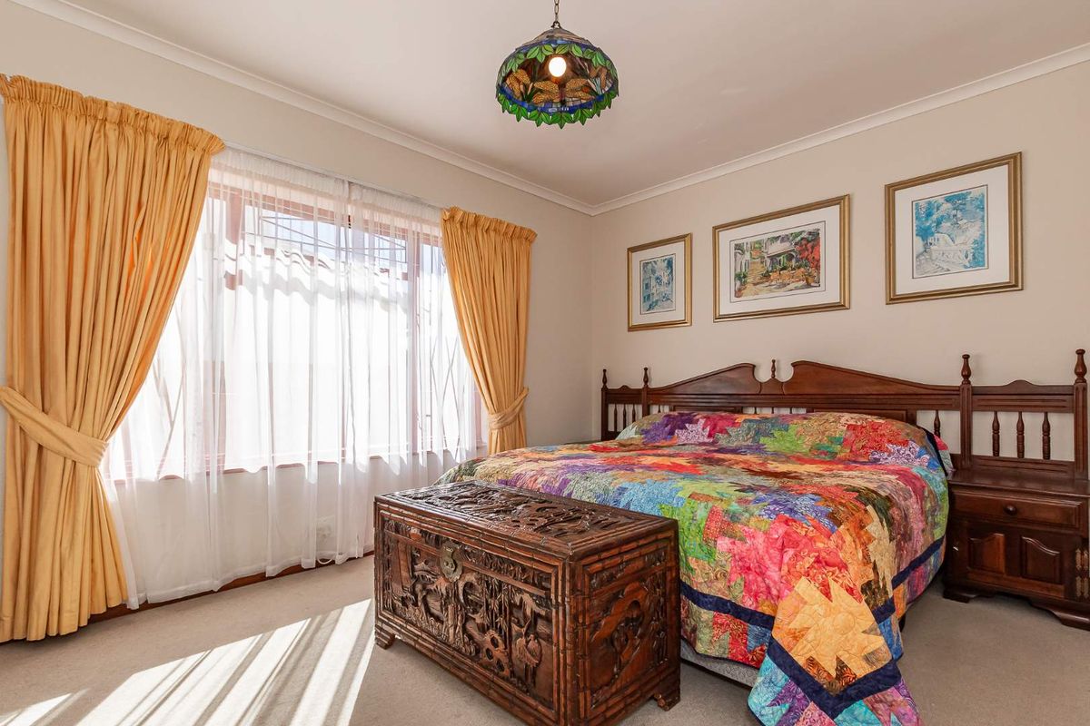 A well-maintained bedroom featuring neutral carpeting, coved ceilings, and a large window allowing for natural light.