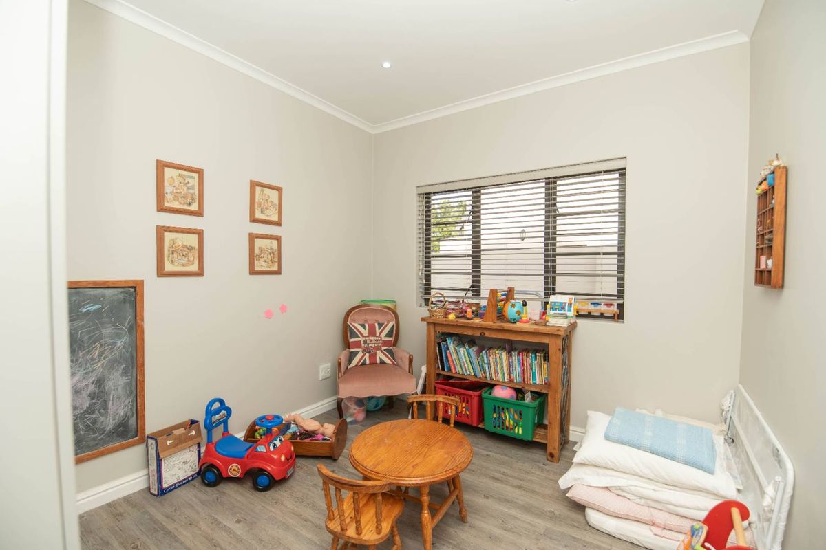 A functional bedroom featuring laminate flooring, recessed downlighting, and venetian blinds, currently utilized as a children's play area.