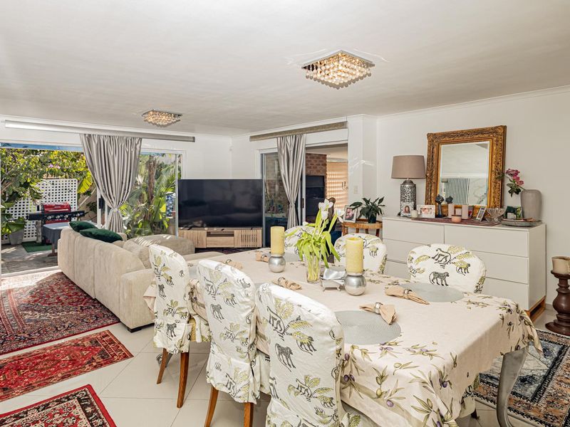 Spacious open-plan living and dining area featuring tiled flooring, modern ceiling lighting, and large sliding glass doors providing seamless access to the outdoor patio.