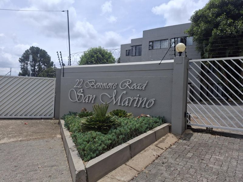 Front entrance view of the San Marino apartment complex at 22 Benmore Road, featuring a secure gated access point and perimeter wall.