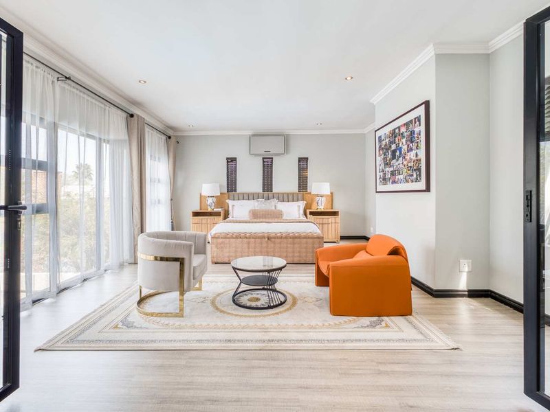 Spacious bedroom featuring light laminate flooring, recessed lighting, crown molding, and large sliding glass doors providing ample natural light.