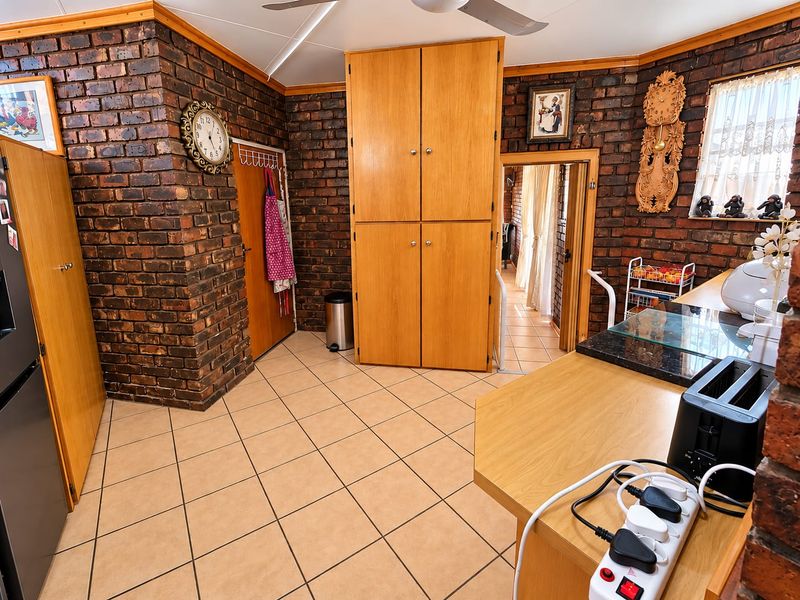 A kitchen featuring exposed brick walls, tiled flooring, and built-in wooden cabinetry with granite countertops.