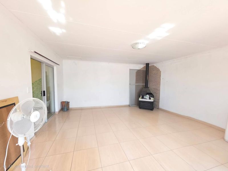 Spacious living area featuring neutral tiled flooring, a built-in fireplace, and sliding glass doors providing access to the exterior.